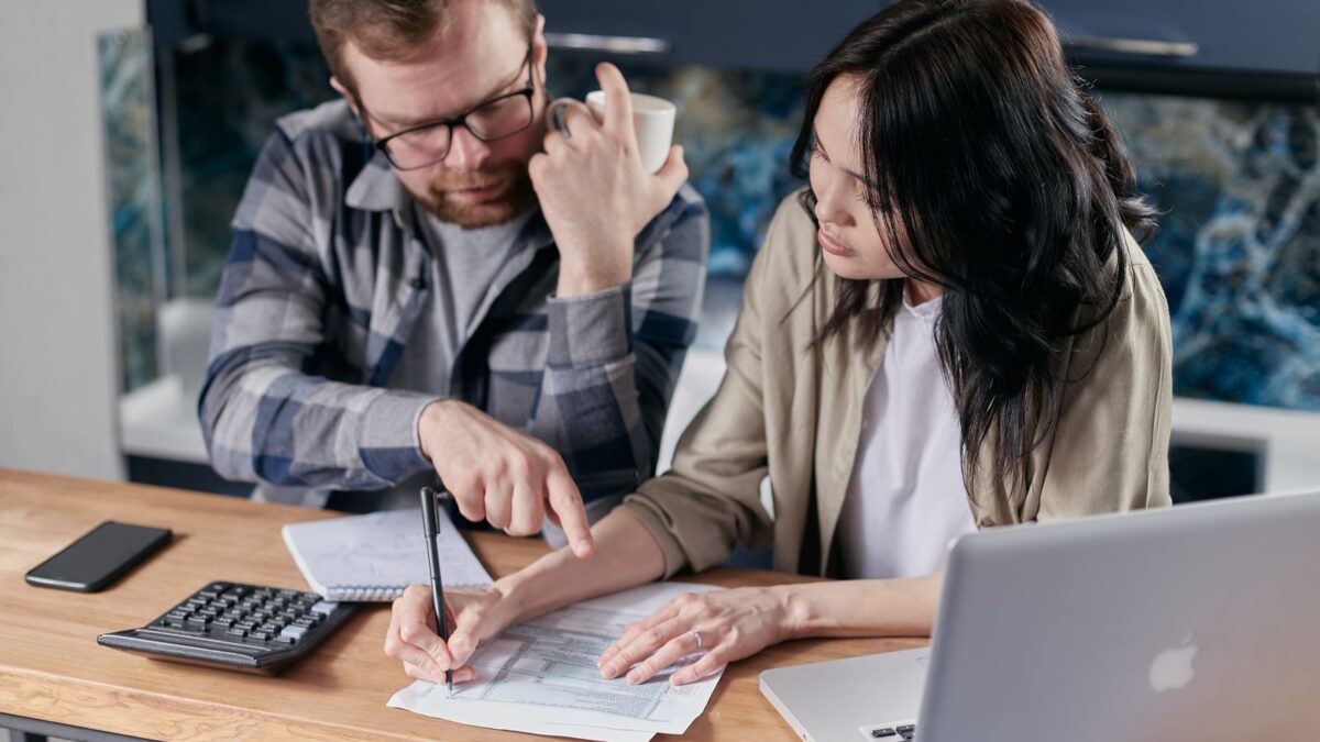 Una pareja revisa documentos financieros con calculadora y laptop