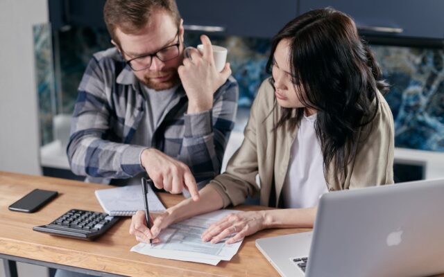 Una pareja revisa documentos financieros con calculadora y laptop