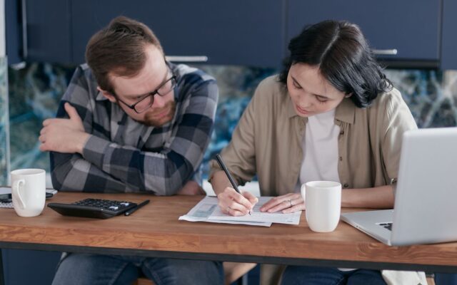 Dos personas revisan documentos frente a una laptop