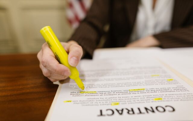 Una mano señala cláusulas específicas en un contrato