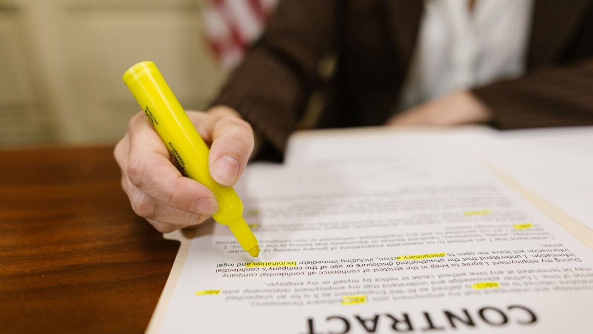 Una mano señala cláusulas en un contrato