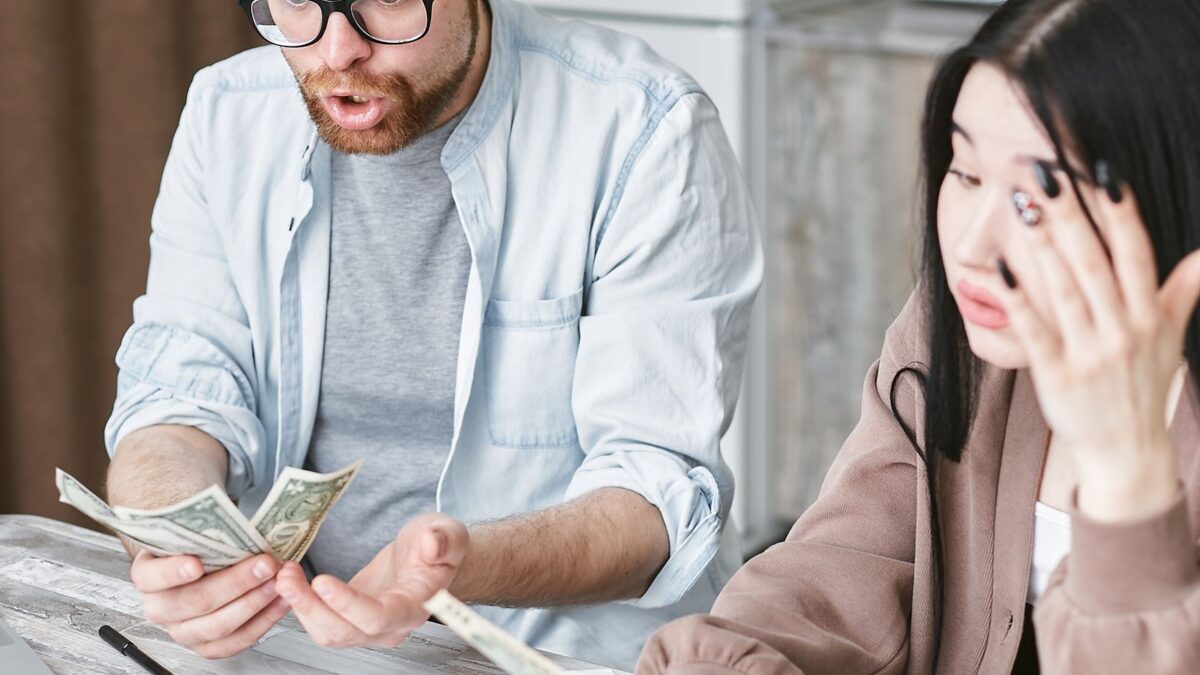 Una pareja cuenta dinero en casa con gesto de preocupación