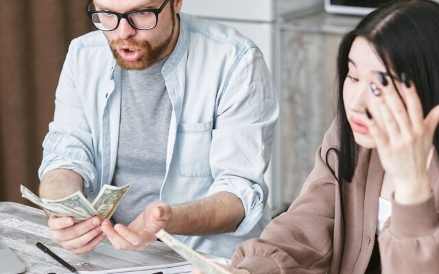 Una pareja cuenta dinero en casa con gesto de preocupación