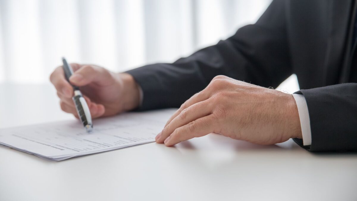 Una persona firma documentos en un escritorio