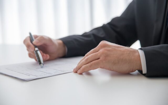 Una persona firma documentos en un escritorio